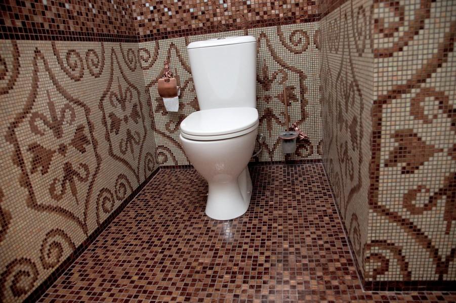 Для отделки потолка и стен в туалете можно использовать мозаику, позволяющую сделать сплошное покрытие, идеально сочетающееся с керамической плиткой